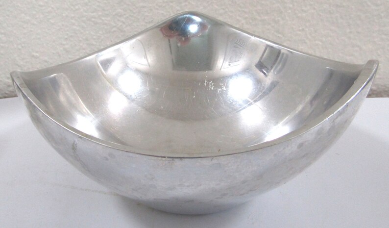 Puede incluir: Un taz&oacute;n de metal plateado con un dise&ntilde;o curvo &uacute;nico. El taz&oacute;n es liso y reflectante.