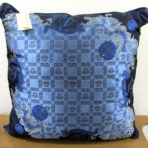 May include: Blue and black patterned throw pillow with a repeating Greek key design and floral accents. The pillow has a black border and a subtle sheen.
