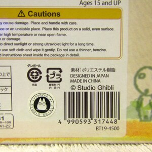 May include: A cardboard box with a yellow and brown design. The box features a cartoon character with large eyes and a small mouth. The box also includes the text "Studio Ghibli" and a barcode. The box is for ages 15 and up.