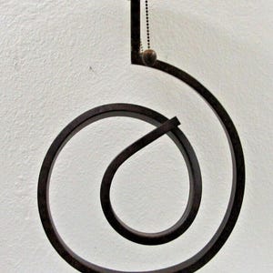 May include: A decorative table lamp with a unique, swirling metal base and a frosted glass shade. The lamp features a brown metal frame with a clear glass base and a pull chain. The shade is a flat, circular shape.