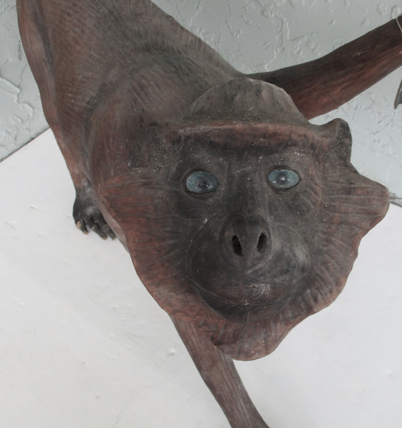 May include: A wooden monkey sculpture with blue eyes. The monkey is standing on all fours and has a long tail.