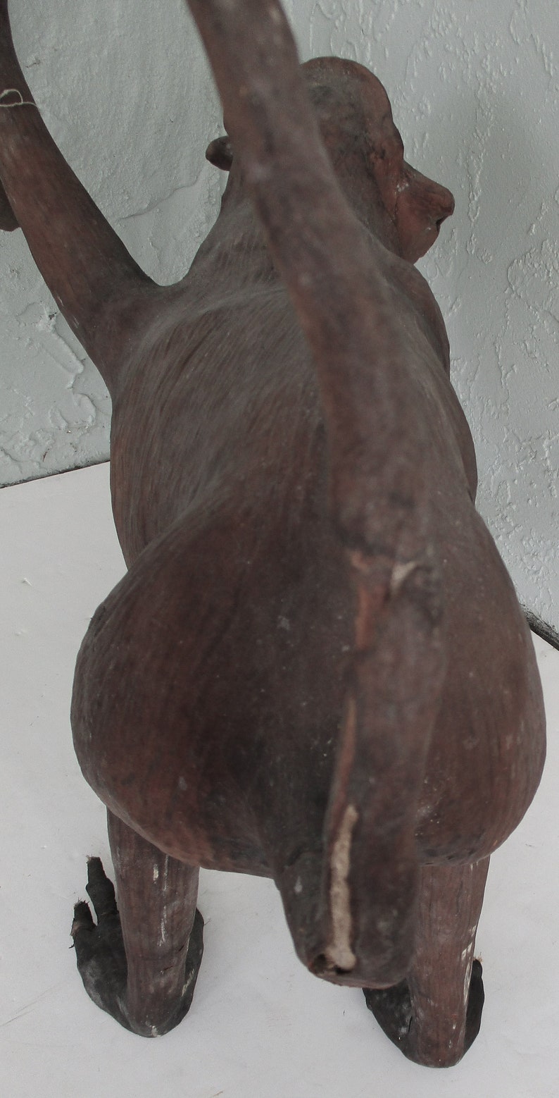 May include: A brown, wooden monkey sculpture with a long tail. The monkey is standing on all fours and its head is turned to the side.