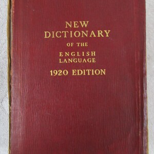 May include: A red, leather-bound book with gold lettering that reads "NEW DICTIONARY OF THE ENGLISH LANGUAGE 1920 EDITION".