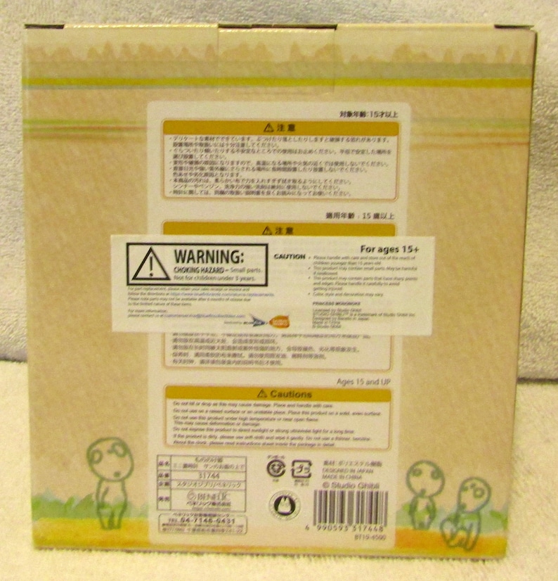 May include: A cardboard box with a warning label for ages 15 and up. The box features a cartoon character with a large head and small body. The text on the box reads "Studio Ghibli".