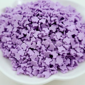 May include: A large pile of purple butterfly-shaped sprinkles. The sprinkles are small and have a slightly raised texture.