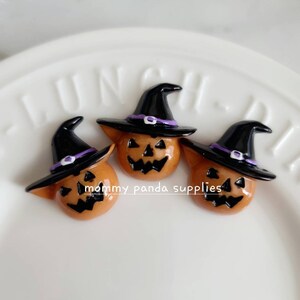 Peut inclure: Trois décorations d'Halloween en forme de citrouille orange avec des chapeaux de sorcière noirs et des bandes violettes. Les chapeaux ont une pointe pointue et un large bord.
