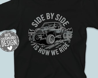 May include: Black t-shirt with a circular graphic featuring an off-road vehicle and the text "SIDE BY SIDE IS HOW WE RIDE." A small, round graphic on the left says "100% CUSTOMIZABLE DESIGN." The shirt also has the text "THE REALLY NICE STUFF."