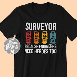 May include: Black t-shirt with a white graphic that says "SURVEYOR" with a vintage-style illustration of four surveying instruments. The text below the instruments says "Because engineers need heroes too".