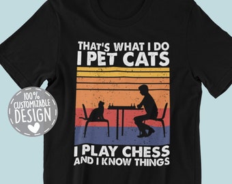 May include: Black t-shirt with a vintage-style graphic design. The graphic features a person playing chess with a cat sitting on a chair. The text reads "That's what I do I pet cats I play chess and I know things".