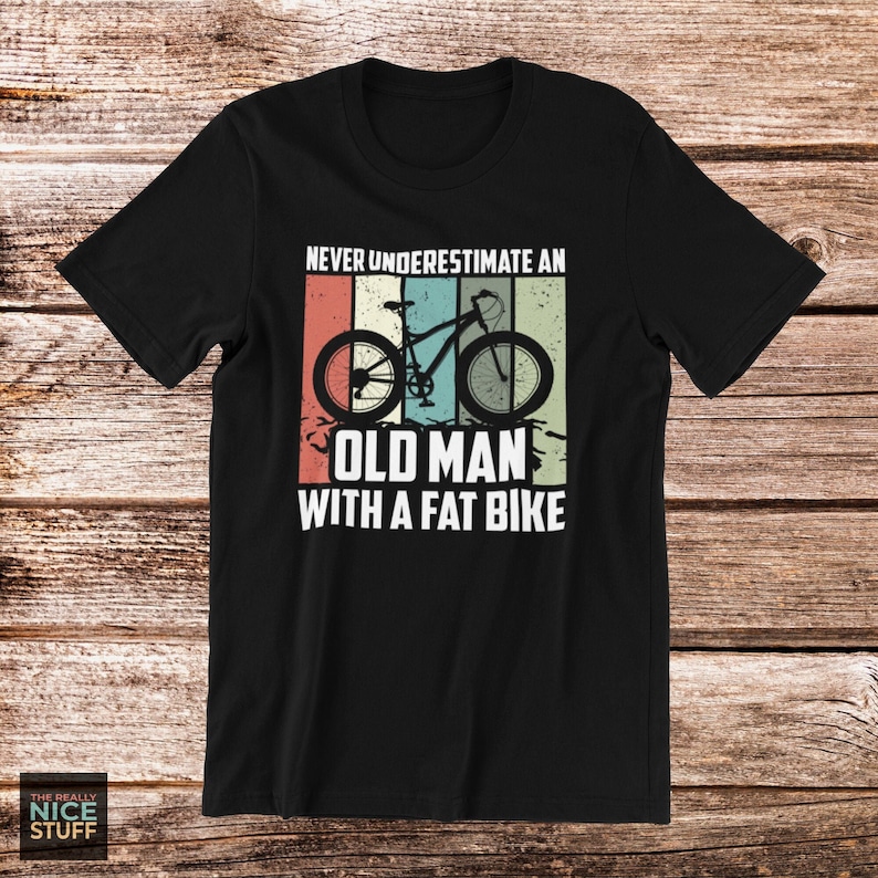 May include: Black t-shirt with a vintage-style graphic of a bicycle and the text "Never underestimate an old man with a fat bike."