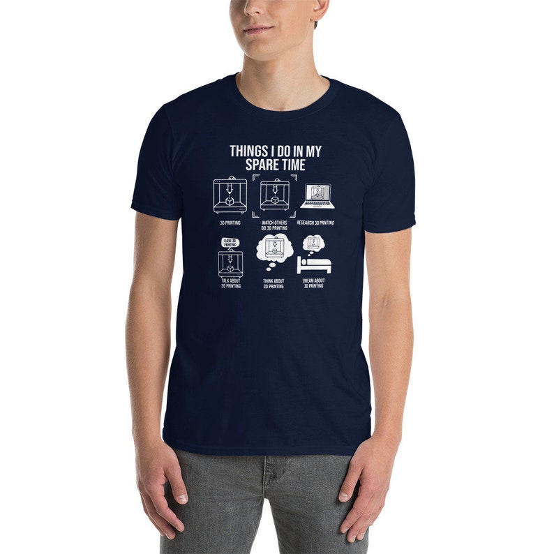 Puede incluir: Una camiseta azul marino con un gr&aacute;fico blanco que dice "Things I do in my spare time" y muestra una serie de ilustraciones de impresoras 3D, una computadora y una persona durmiendo. Las ilustraciones est&aacute;n acompa&ntilde;adas de texto que describe actividades relacionadas con la impresi&oacute;n 3D.