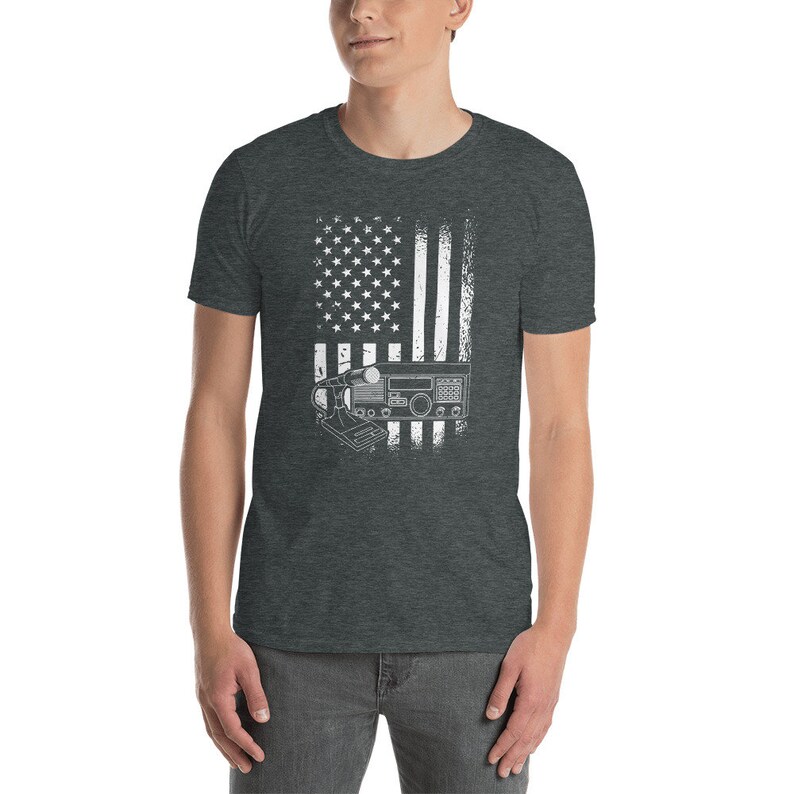 May include: A dark heather grey t-shirt with a white distressed American flag design. A white silhouette of a CB radio is superimposed over the flag.