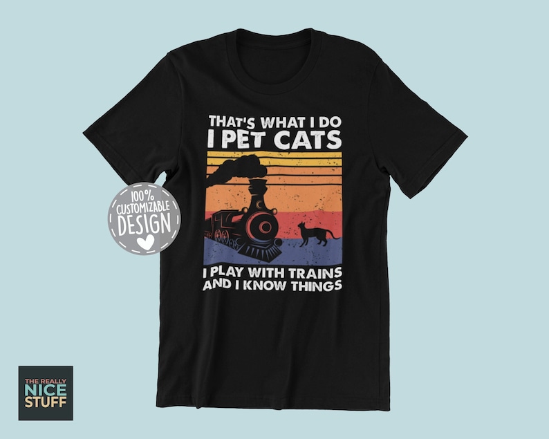 May include: Black t-shirt with a vintage-style graphic of a train and a cat. The text reads "That's what I do I pet cats I play with trains and I know things".