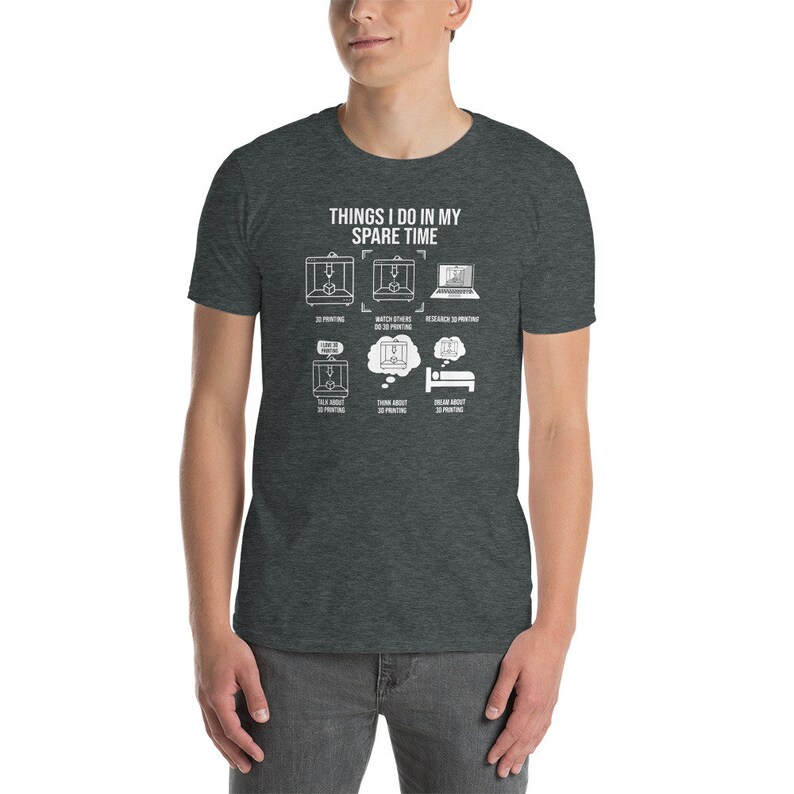 Puede incluir: Una camiseta gris oscuro jaspeada con un gr&aacute;fico blanco que dice "Things I do in my spare time" y muestra una serie de iconos que representan actividades de impresi&oacute;n 3D. Los iconos incluyen impresi&oacute;n 3D, ver a otros hacer impresi&oacute;n 3D, investigar sobre impresi&oacute;n 3D, hablar sobre impresi&oacute;n 3D, pensar en impresi&oacute;n 3D y so&ntilde;ar con impresi&oacute;n 3D.