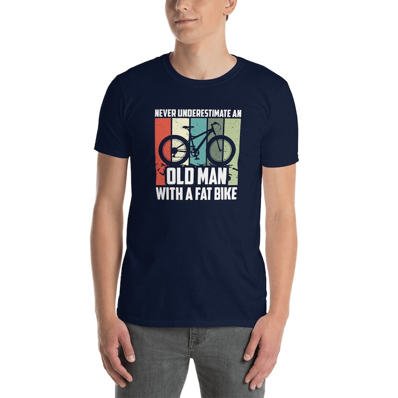 May include: A navy blue t-shirt with a vintage-style graphic of a bicycle and the text "Never underestimate an old man with a fat bike."