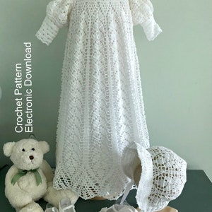 May include: White crocheted baby dress, bonnet and shoes. The dress features a delicate lace pattern and is displayed on a mannequin. The bonnet and shoes are also crocheted and have a matching lace pattern. Crochet Pattern Electronic Download.