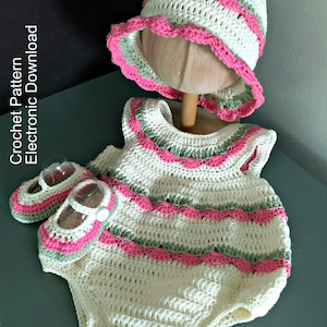 May include: A crocheted baby outfit set in white, pink, and green. The set includes a hat, a sleeveless dress, and a pair of shoes. The outfit is decorated with a scalloped trim.