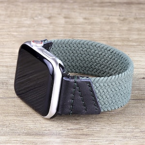 May include: A green and black braided watch band with a silver Apple Watch.