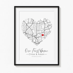 May include: A framed wall art print featuring a black and white street map shaped like a heart with a small red heart icon marking a specific location. Below the map, the text reads Our First Home, Chloe & Adam, and 18 Parkside Road.