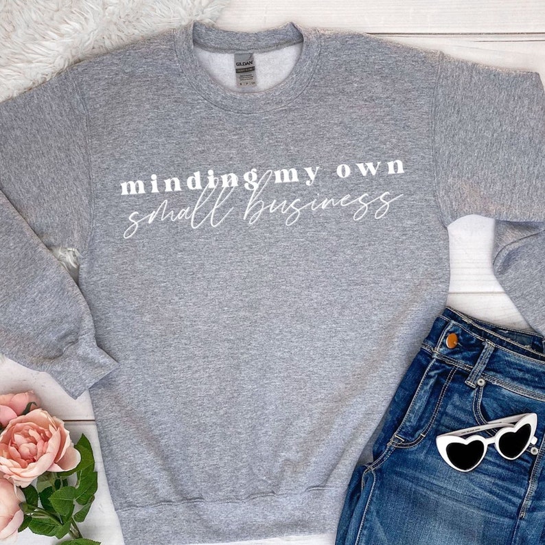 K&ouml;nnte beinhalten: Ein grauer Pullover mit dem Aufdruck "minding my own small business" in wei&szlig;.