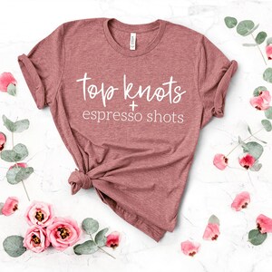 May include: A mauve t-shirt with the text "top knots + espresso shots" in white lettering.