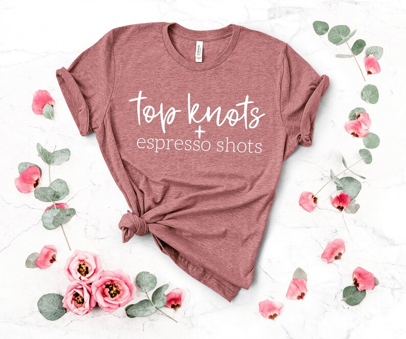 May include: A mauve t-shirt with the text "top knots + espresso shots" in white lettering.