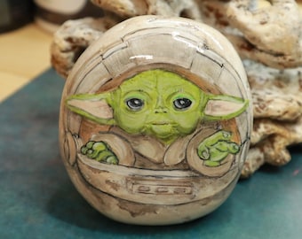 Baby Yoda(aka Grogu) In Crib Pod fanart on painted rock.