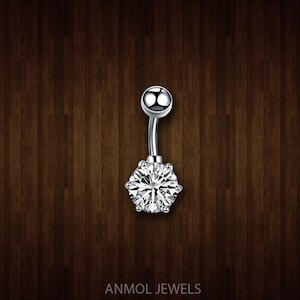May include: A silver belly button ring with a large, clear, round-cut cubic zirconia gemstone. The curved barbell design features a small, shiny ball at the top and a sparkling, six-prong set stone at the bottom. The text "ANMOL JEWELS" is at the bottom.