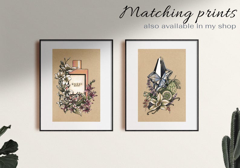 Pu&ograve; includere: Due stampe incorniciate di flaconi di profumo con illustrazioni floreali. La stampa a sinistra presenta una bottiglia Gucci Bloom rosa con fiori bianchi. La stampa a destra presenta una bottiglia argentata con un tappo a forma di stella e fiori bianchi.