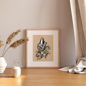 Pu&ograve; includere: Una stampa incorniciata di un'illustrazione stilizzata di un flacone di profumo con un tappo a forma di stella. Il flacone &egrave; circondato da fiori, foglie e frutti, tra cui un lime e baccelli di vaniglia. Lo sfondo &egrave; di colore marrone chiaro.