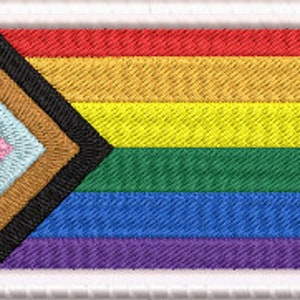 May include: Embroidered rectangular patch featuring the Progress Pride flag. The flag design includes the traditional rainbow stripes, along with a chevron of pink, light blue, brown, black, and white. The patch is framed with a white border.