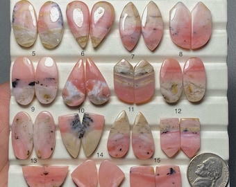 May include: A collection of pink opal gemstones in various shapes, including oval, teardrop, and rectangular. The opals display a range of colors from pale pink to creamy white, with some featuring darker inclusions. A nickel coin is included for size reference.