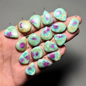 May include: A collection of seventeen polished gemstones, each with a unique shape. The stones feature a mix of colors, including teal, light green, and magenta. The gemstones are numbered 1 through 17.
