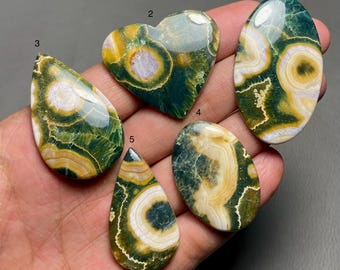 Puede incluir: Cinco cabujones de piedra preciosa pulidos de color verde, blanco y amarillo, en varias formas, incluyendo un corazón, un óvalo y una lágrima.