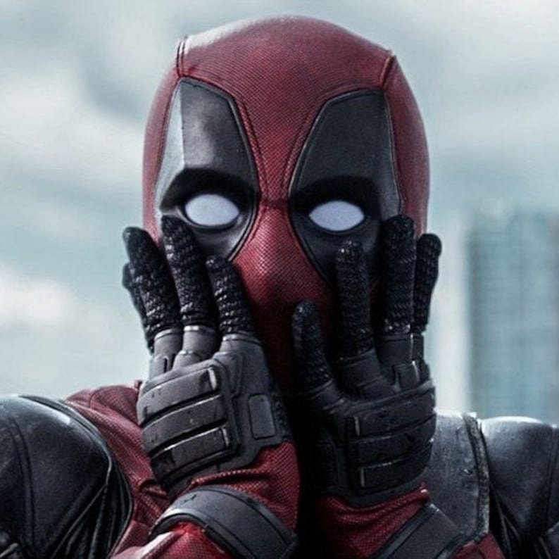 May include: A red and black superhero costume with a white mask and white eyes. The superhero is covering their face with their hands.