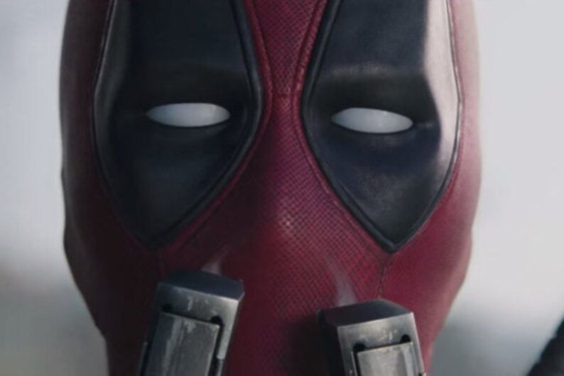 May include: A close-up of a red and black superhero mask with white eyes. The mask has a textured surface and is made of a durable material.