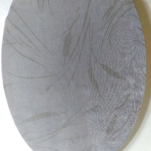 Könnte beinhalten: Ein hellgrauer Toilettensitzbezug mit strukturierter Oberfläche und cremefarbenem Scharnier. Der ovale Bezug hat ein dezentes Muster und ist für eine Standardtoilette konzipiert.