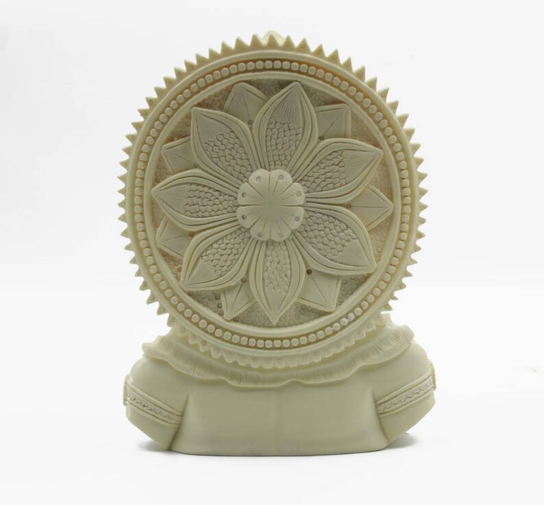 May include: White ceramic sculpture of a deity with a detailed floral design on the back. The sculpture is carved with intricate details and has a smooth, matte finish.