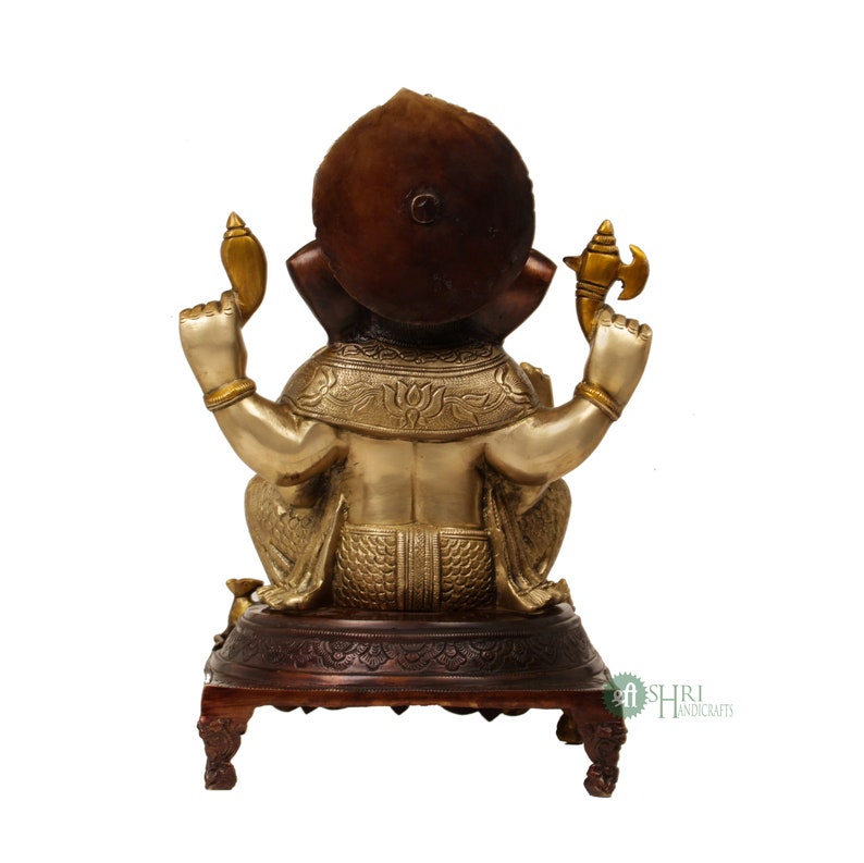 May include: A gold and brown metal statue of Ganesha, the Hindu god of wisdom and prosperity, sitting on a wooden base. The statue is intricately detailed and features a traditional design.