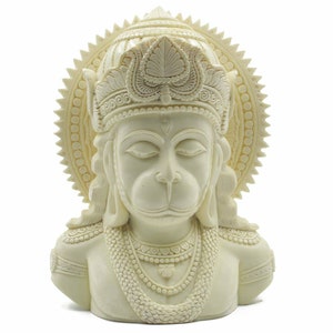 May include: White resin bust sculpture of the Hindu deity Hanuman. The sculpture depicts Hanuman with his eyes closed, wearing a crown and a necklace. The sculpture is detailed with intricate carvings.