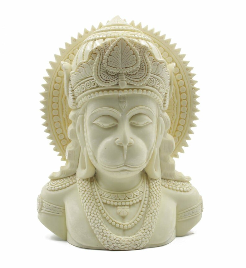 May include: White resin bust sculpture of the Hindu deity Hanuman. The sculpture depicts Hanuman with his eyes closed, wearing a crown and a necklace. The sculpture is detailed with intricate carvings.