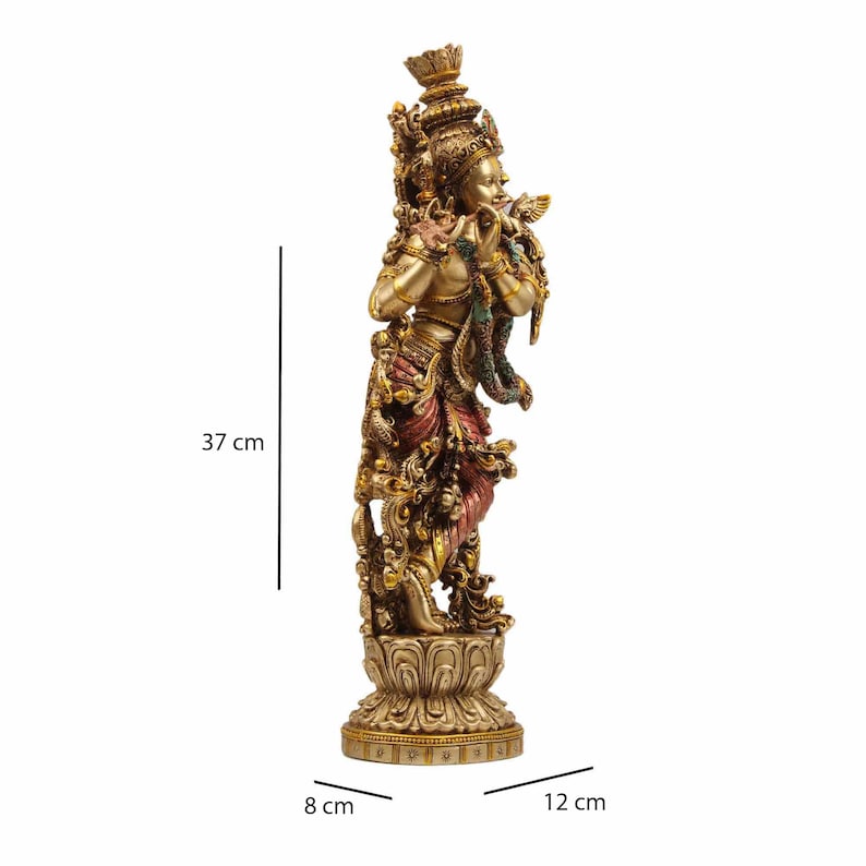 May include: A gold-toned statue of a Hindu deity playing a flute, standing on a lotus-shaped base. The statue is 37 cm tall, 12 cm wide, and 8 cm deep.