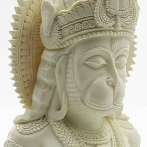 May include: White sculpted bust of the Hindu deity Hanuman, with a detailed crown and closed eyes. The bust is made of a smooth, white material and is a traditional religious art piece.