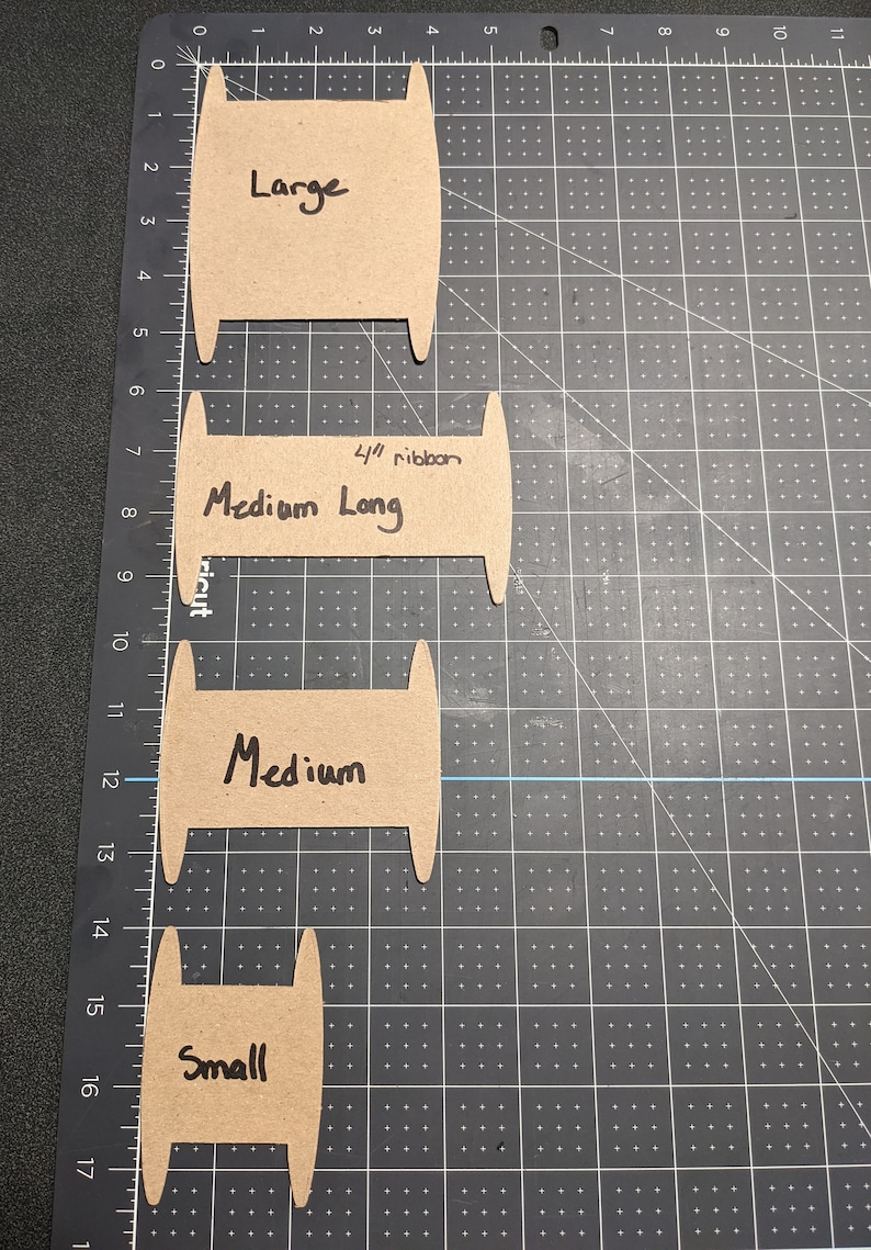 Puede incluir: Cuatro plantillas de carrete de cart&oacute;n para hacer carretes de cinta de diferentes tama&ntilde;os. Las plantillas est&aacute;n etiquetadas como "Large", "Medium Long", "Medium" y "Small".