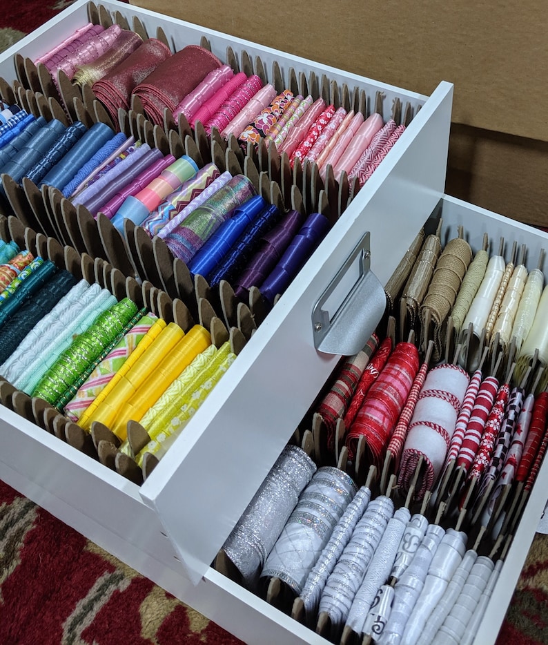 Puede incluir: Un organizador de cajones blanco con dos cajones, el caj&oacute;n superior est&aacute; lleno de cintas de colores, el caj&oacute;n inferior est&aacute; lleno de cintas blancas y plateadas.