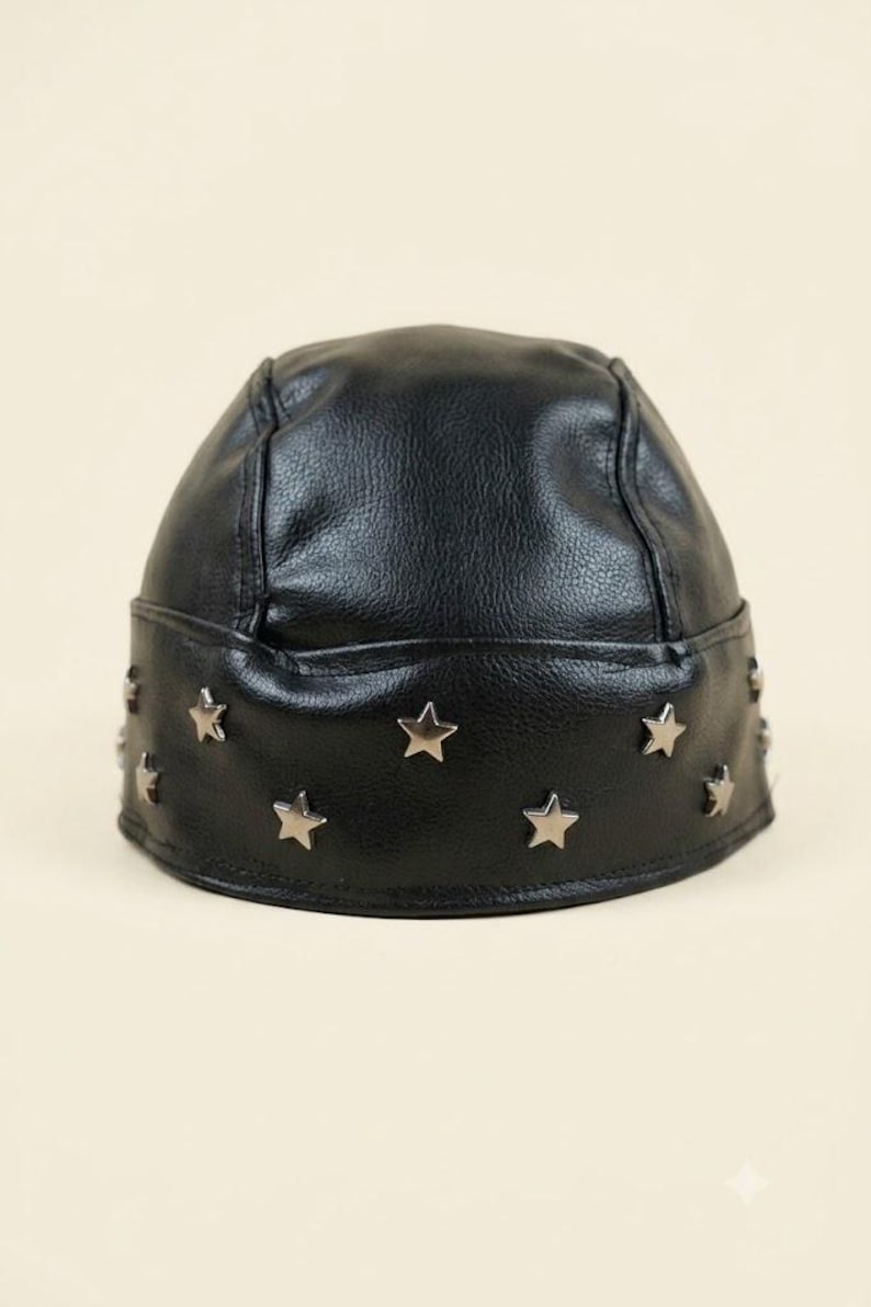 May include: A black faux leather skull cap featuring a textured surface and a wide band around the base. The band is decorated with multiple small, silver-toned metal star-shaped studs evenly spaced around the entire circumference of the hat.