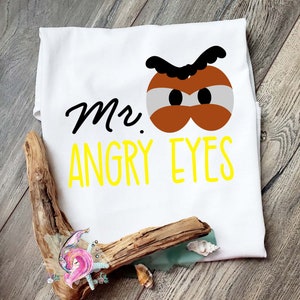 May include: White t-shirt featuring a cartoon illustration of a pair of angry eyes and the text "Mr. Angry Eyes" in yellow.