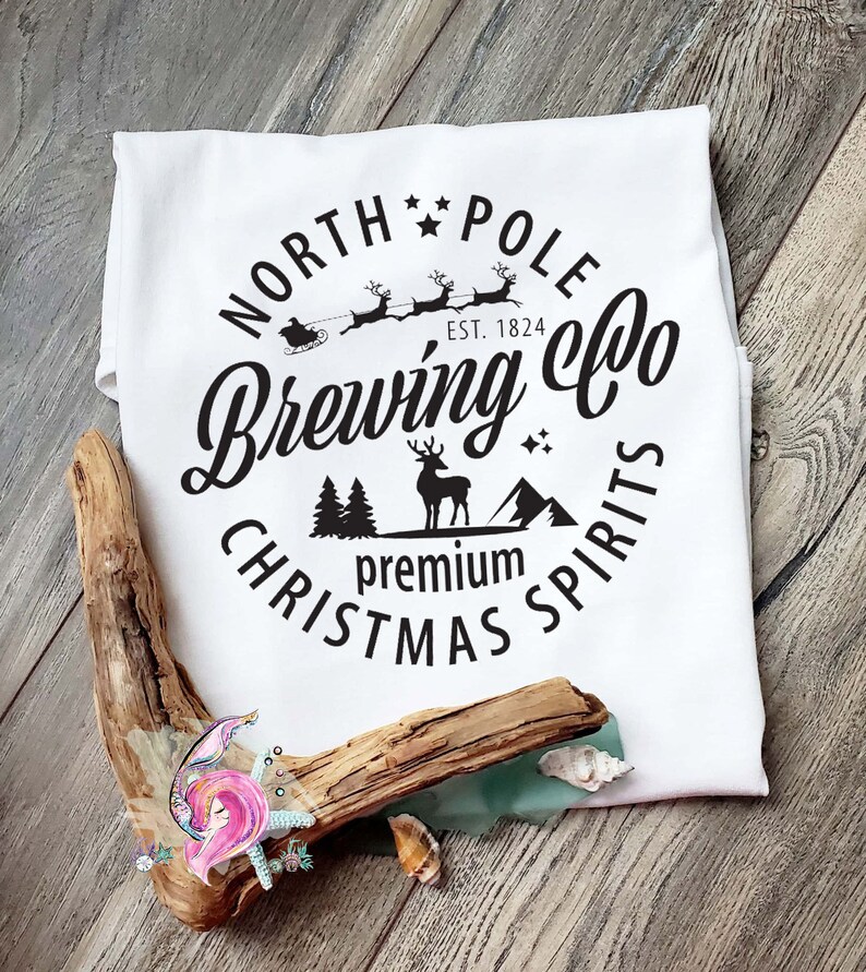 May include: White t-shirt with a black circle design that says "North Pole Brewing Co. Est. 1824 Premium Christmas Spirits". The design includes a reindeer, a Christmas tree, and a sleigh with Santa's reindeer.