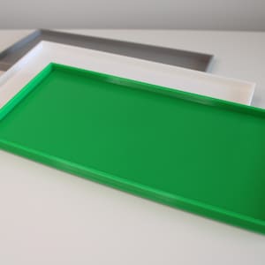 May include: A bright green rectangular tray with a raised edge. The tray is made of plastic and has a smooth surface.