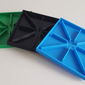 May include: Three square plastic trays with a starburst design. The trays are green, black, and blue.
